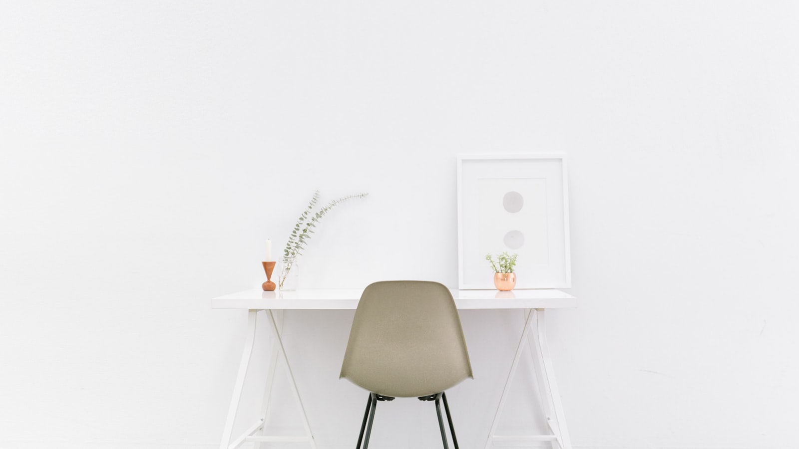 A wooden dining table set with simple place settings in a bright room, surrounded by chairs.