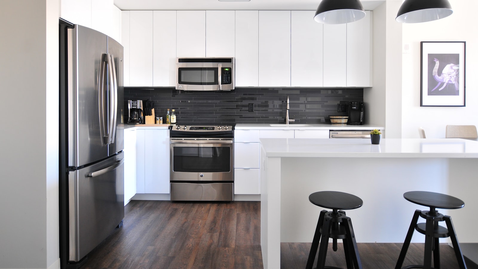 A bright, compact kitchen with pale cabinets, open shelving, and a clear, uncluttered countertop