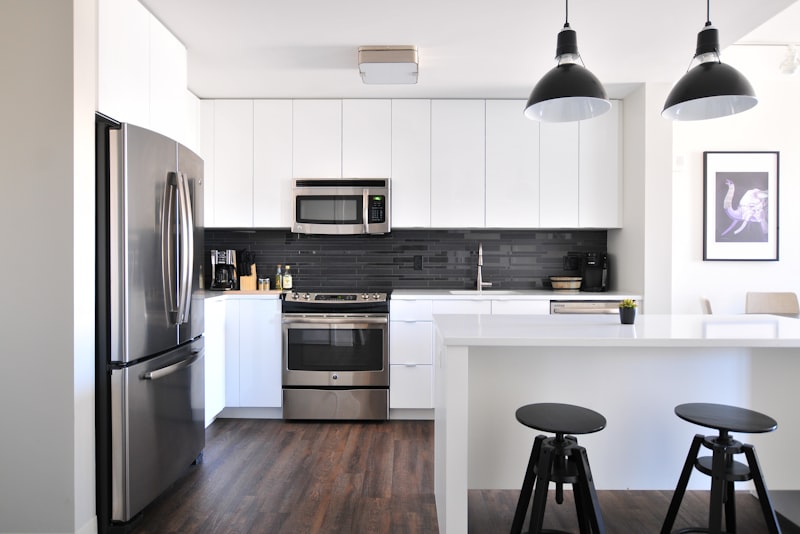 A bright, compact kitchen with pale cabinets, open shelving, and a clear, uncluttered countertop