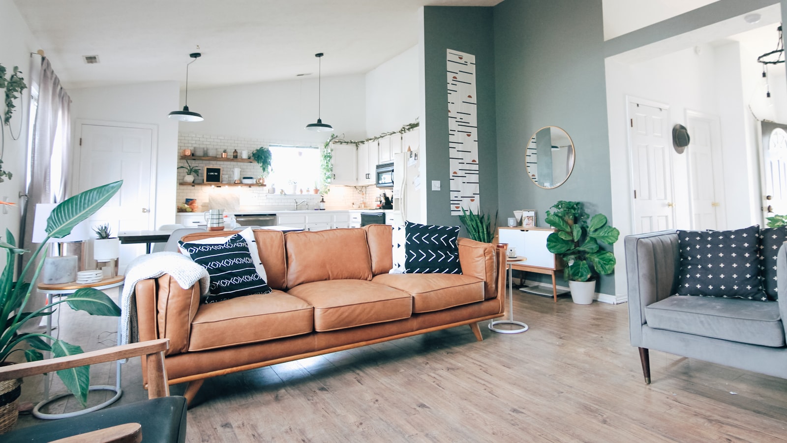 A compact light-toned sofa on slim legs in a cozy small living room with cushions and a side table