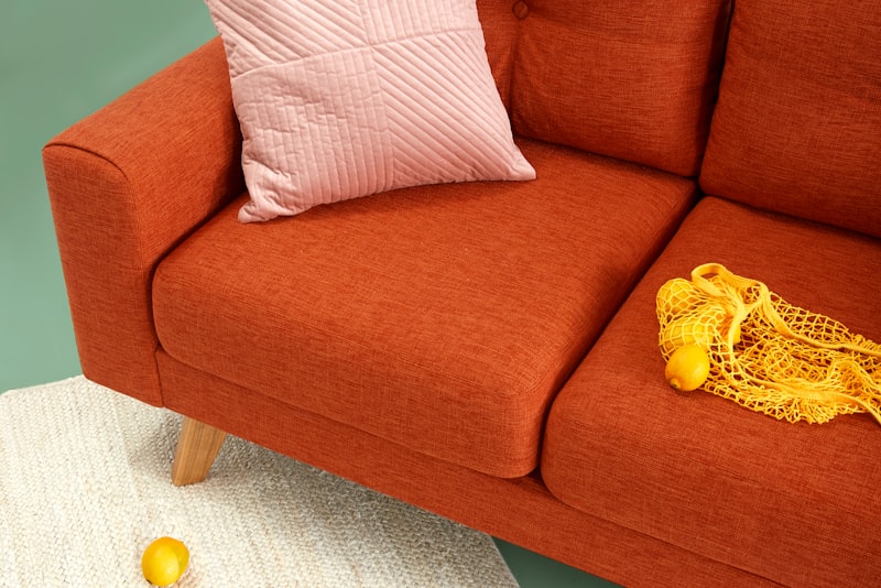 A cozy living room corner with layered throws, a warm lamp, and a small vase of seasonal branches.