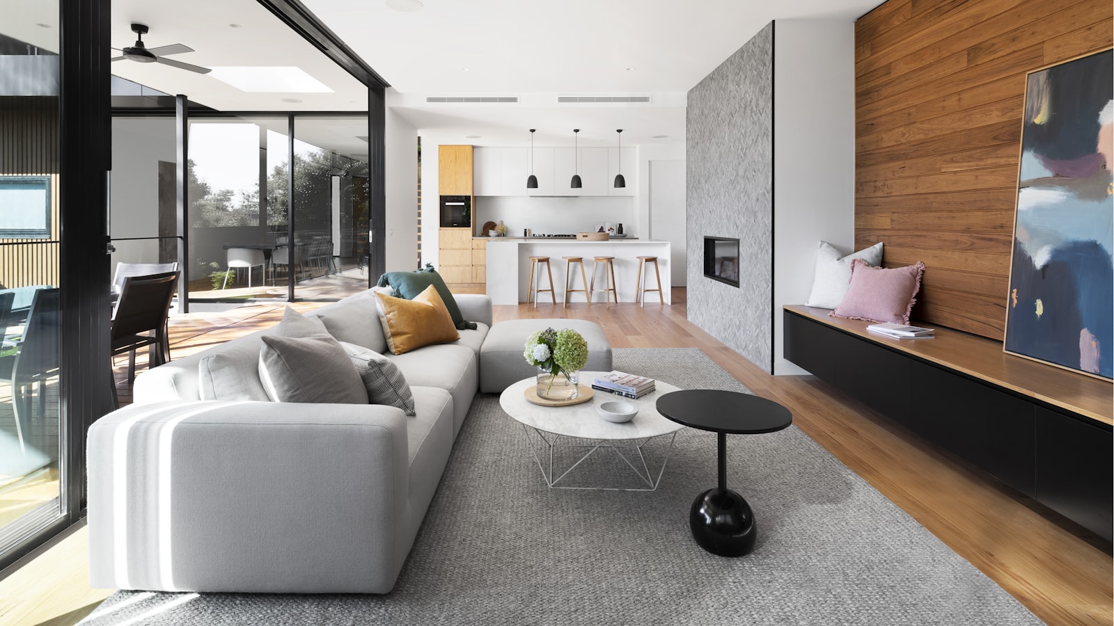 A bright Scandinavian living room with pale wood floors, a soft neutral sofa, and a chunky knit throw
